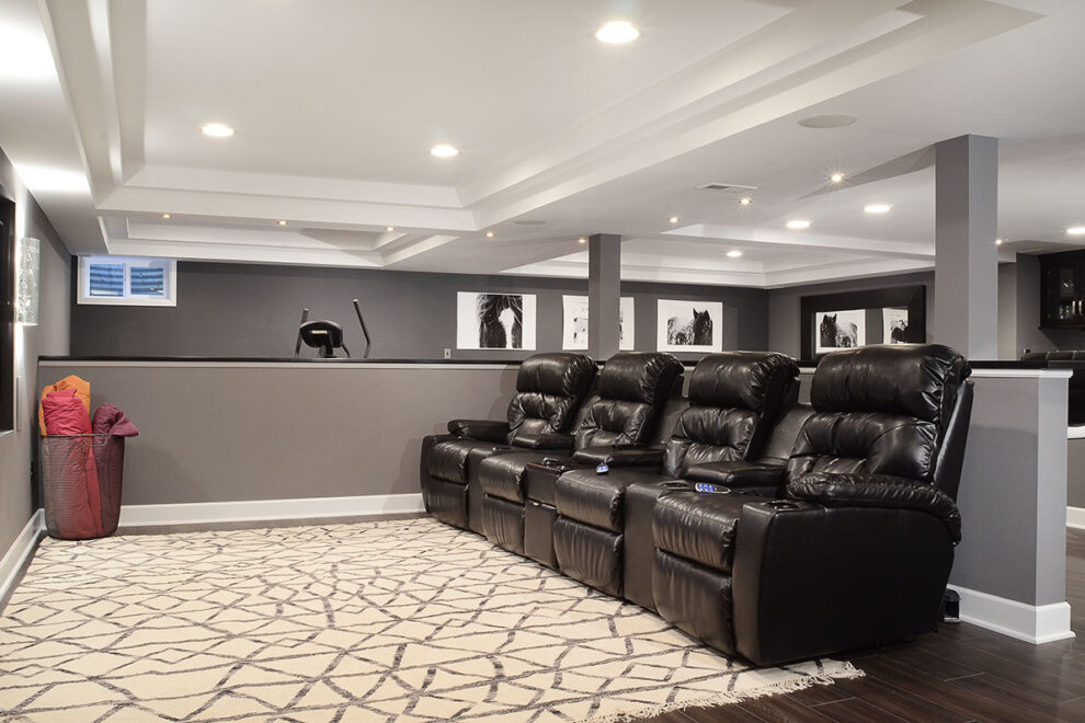 View of a media room with comfortable chairs for watching movies and an exercise area in the background. All part of a walkout basement remodel by B&B.