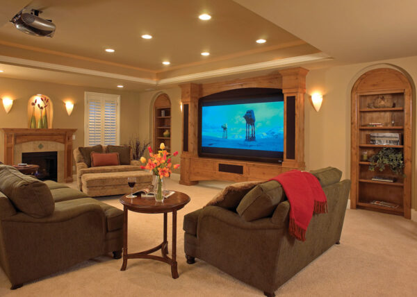 Family room with large built-in television, comfortable sofas, recessed lighting and a fireplace.