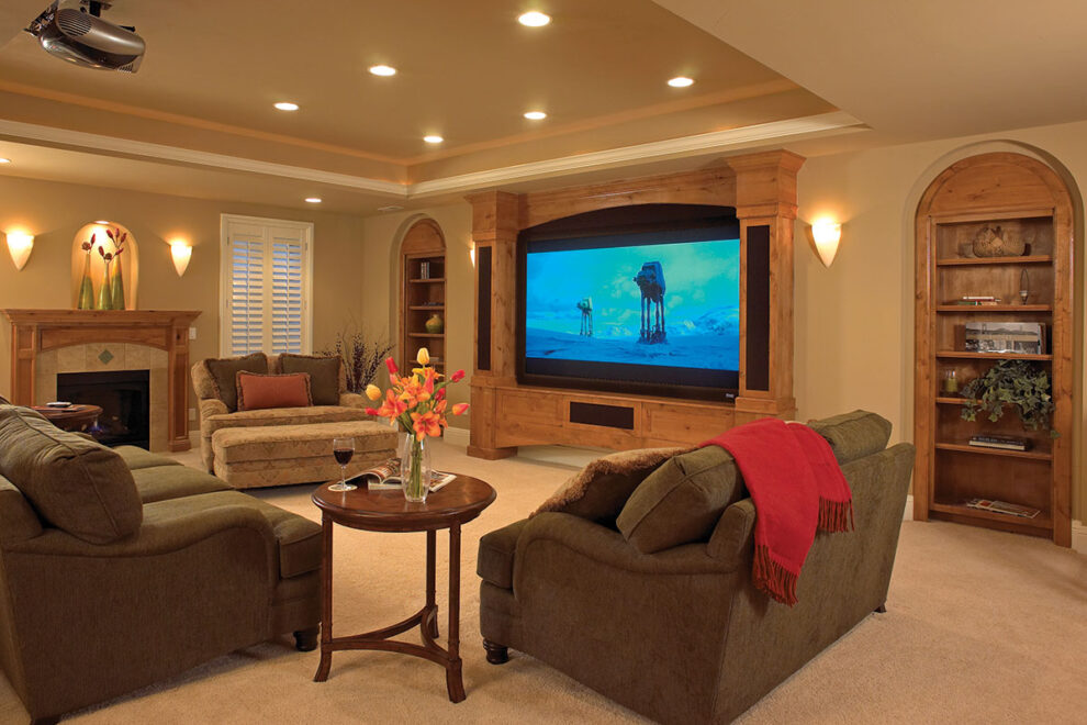 Family room with large built-in television, comfortable sofas, recessed lighting and a fireplace.