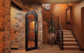 Stairway entrance to basement with beautiful iron work on the stairs and the door leading to the wine cellar.