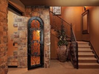 Stairway entrance to basement with beautiful iron work on the stairs and the door leading to the wine cellar.